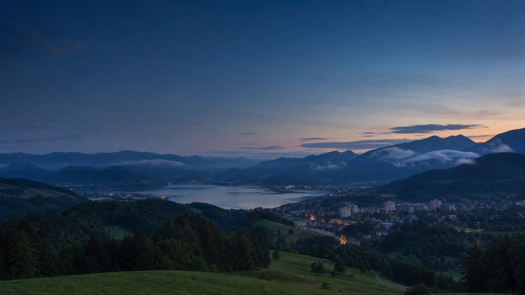 Stilisierte südösterreichische Perspektive mit Alpenraum, See, Stadt und verbindenden Wegen bei einsetzender Dämmerung